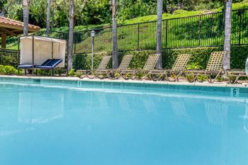 A pool with a blue tinted water and chairs around it.